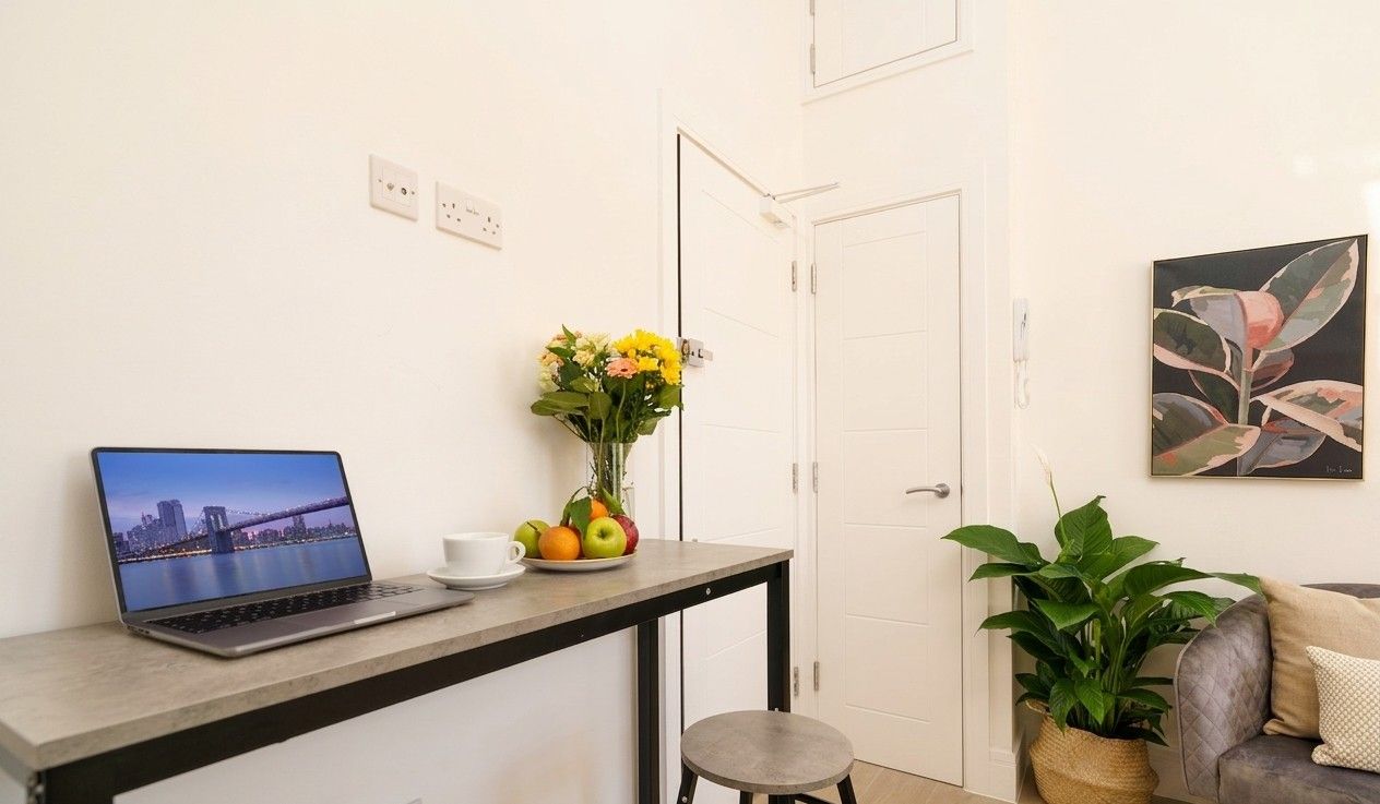 Quiet desk corner with a laptop, flowers and a plant beside a soft armchair