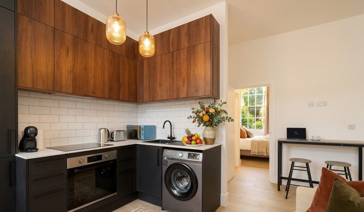 Walnut and black kitchen with white metro tiles, fresh flowers and a fruit bowl, opening onto the bedroom